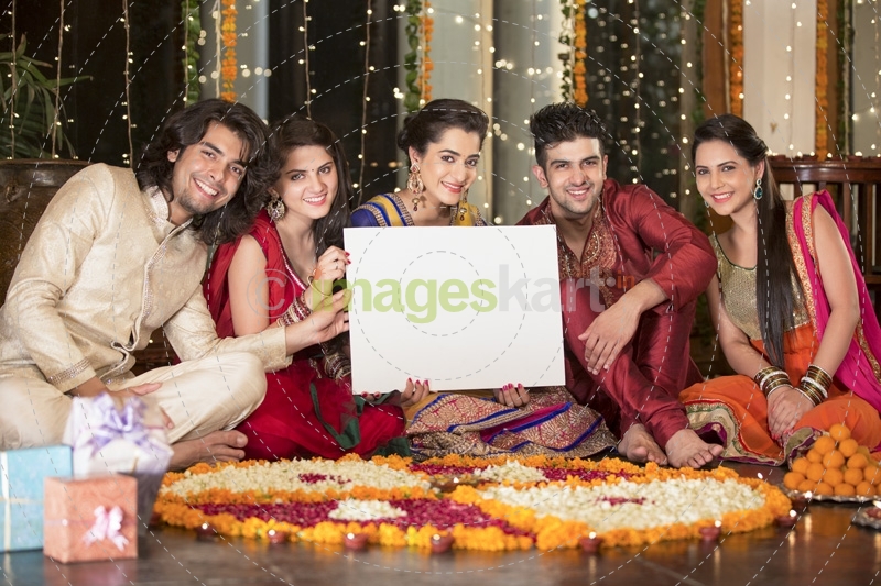 couples in traditional wear sitting with a message board 