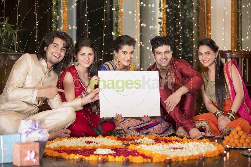 couples in traditional wear sitting with a message board 