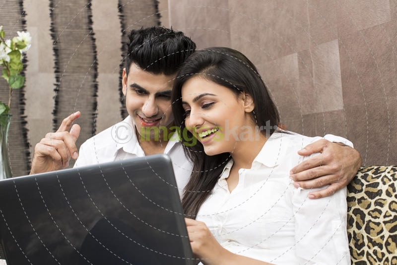 young couple having fun time while browsing in laptop