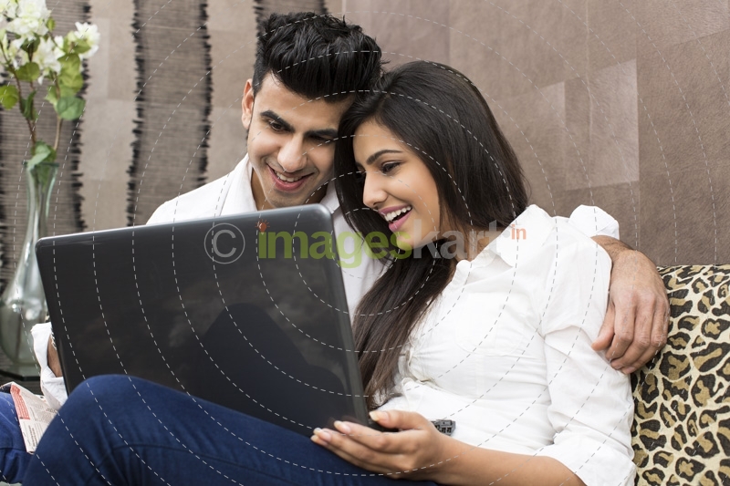 couple sitting on couch browsing on laptop