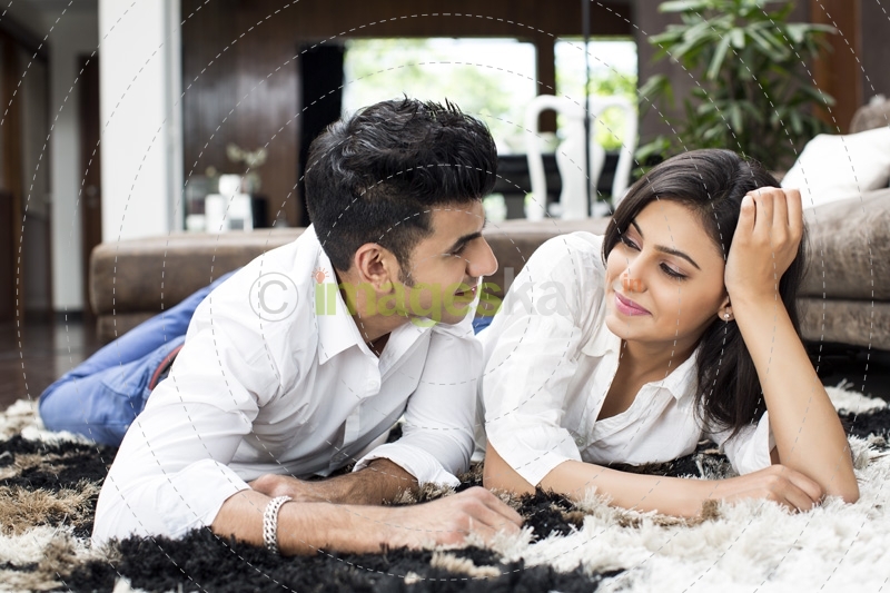 couple lying on rugs and looking at each other