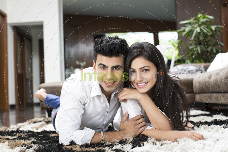 couple lying on rugs and looking at the camera while posing