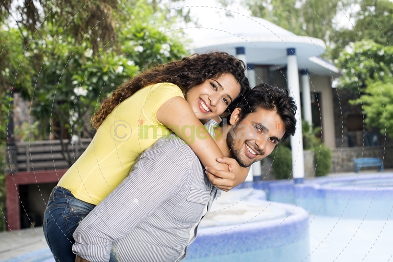 man carrying woman on back outside villa