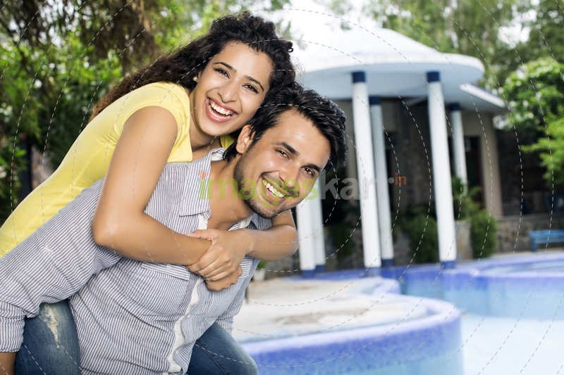 man carrying woman on back outside villa