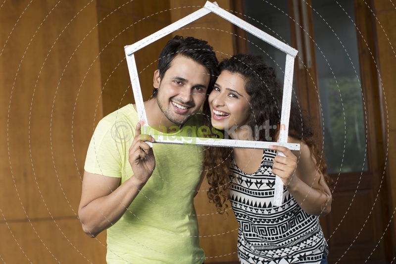 couple posing with house shaped frame