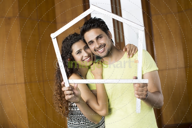 couple posing with house shaped frame