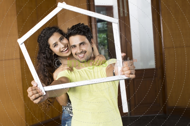 couple posing with house shaped frame
