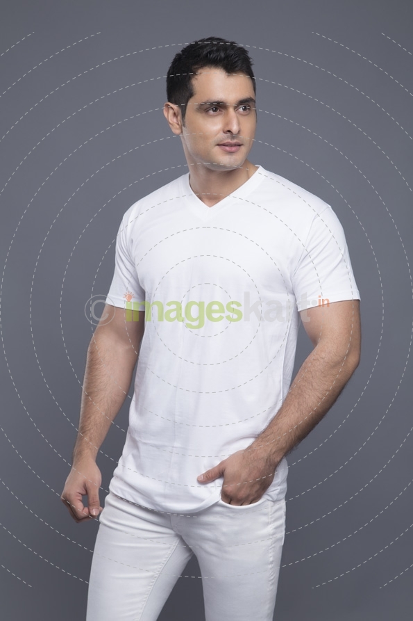 man in white standing with hands in pockets 