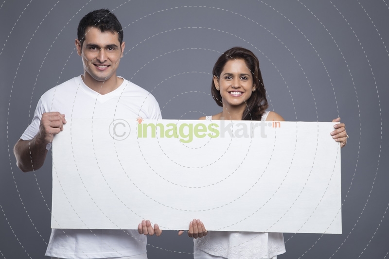 young couple holding a blank poster