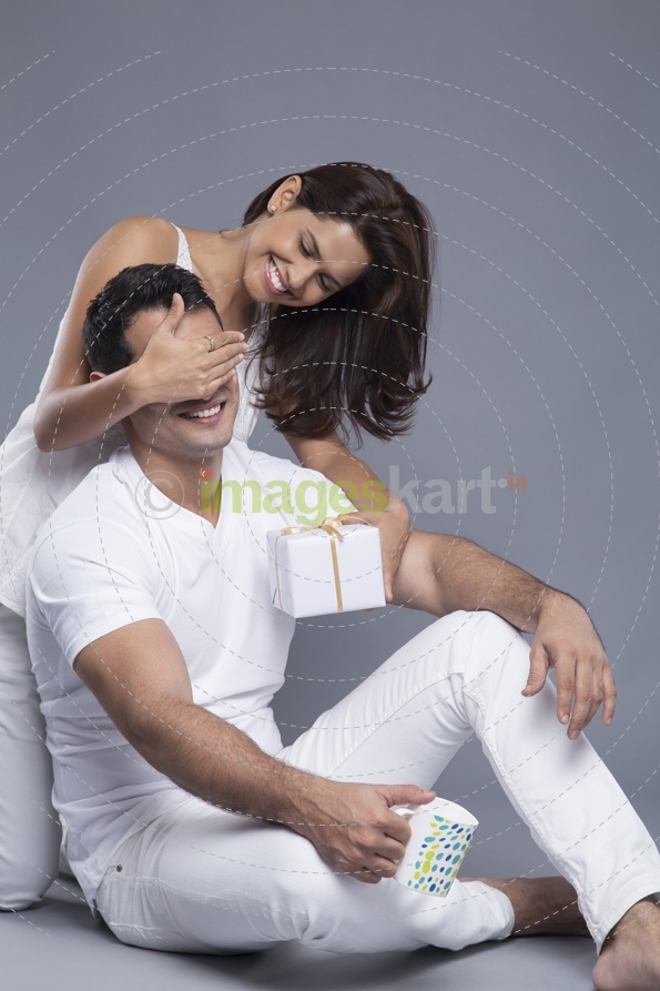 woman covering his husbands eyes for a surprise