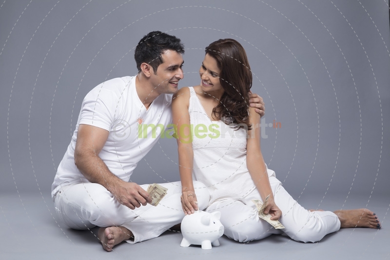 happy couple depositing money in the piggy bank