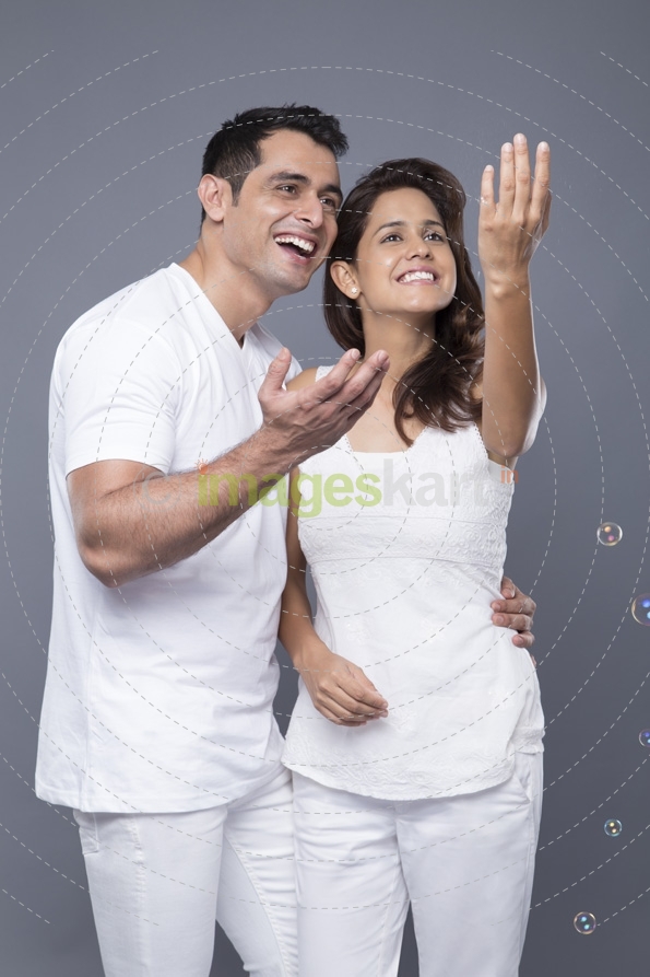couple in white clothes blowing soap bubbles