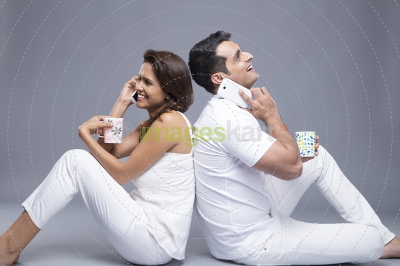 couple talking on the phone while drinking coffee