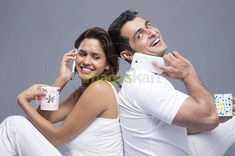 couple talking on the phone while drinking coffee