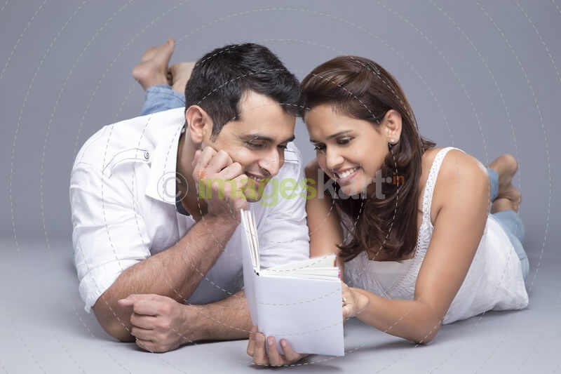 couple reading a book while lying in front view