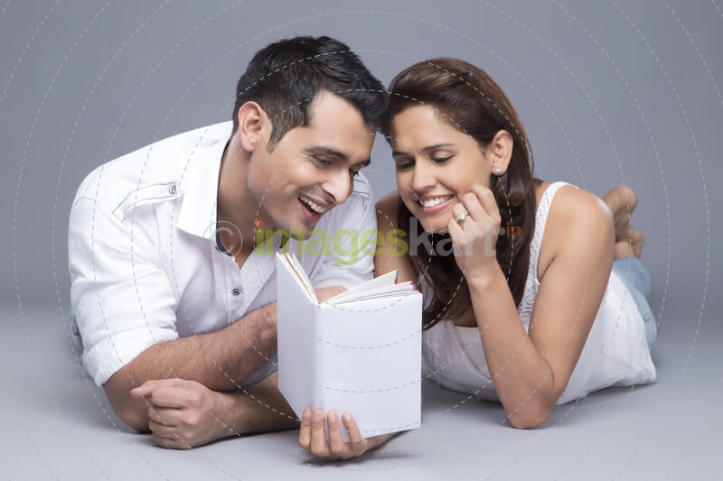 couple reading a book while lying in front view