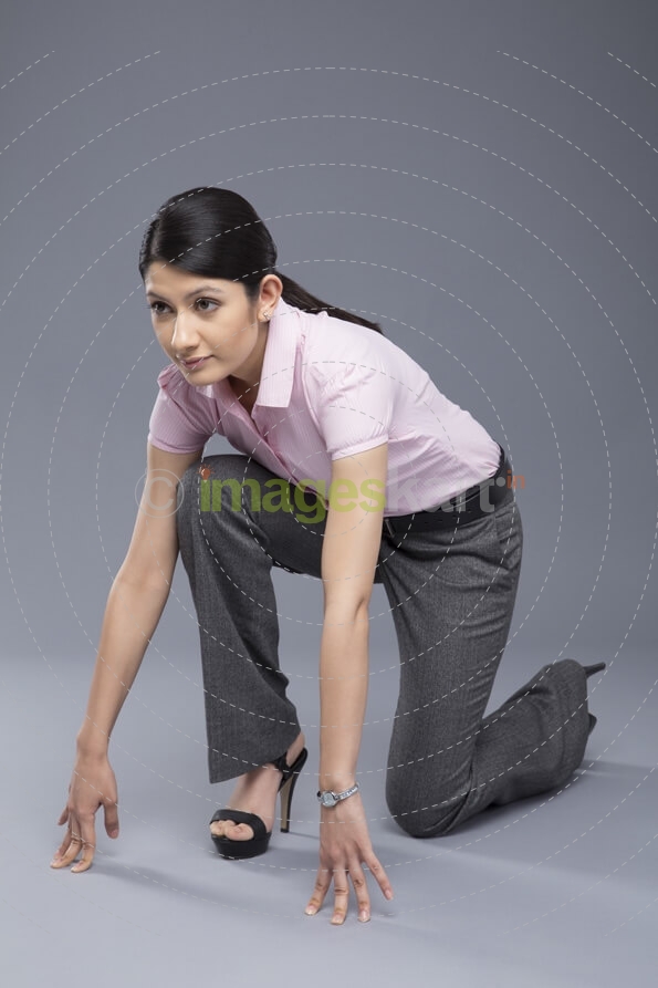 young businesswoman ready to run isolated on grey