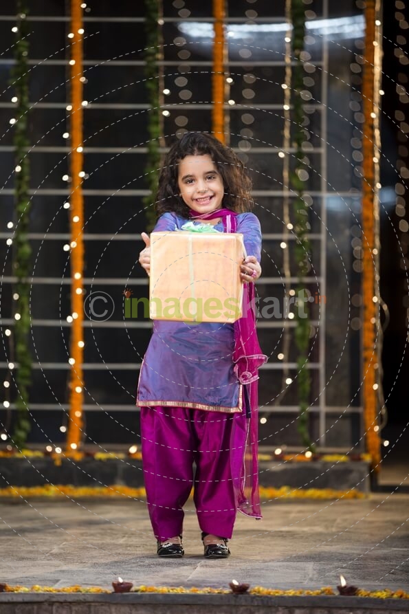 cheerful small girl offering a present on diwali