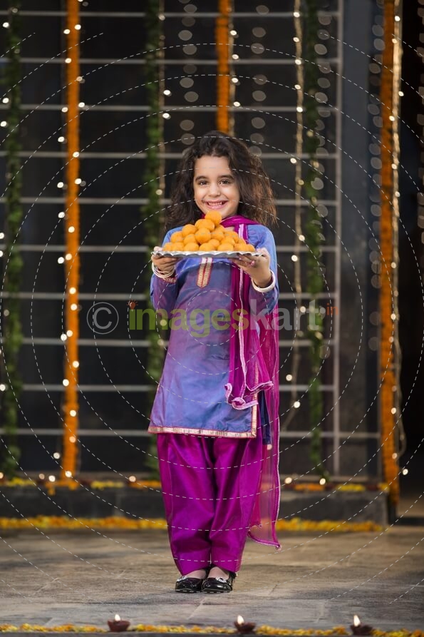 sweet girl holding a thali of laddu on diwali