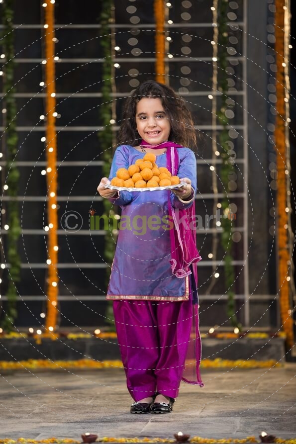 sweet girl holding a thali of laddu on diwali