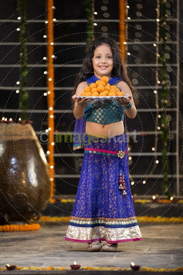 sweet girl holding a thali of laddu on diwali