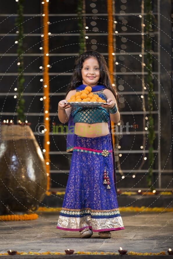 sweet girl holding a thali of laddu on diwali
