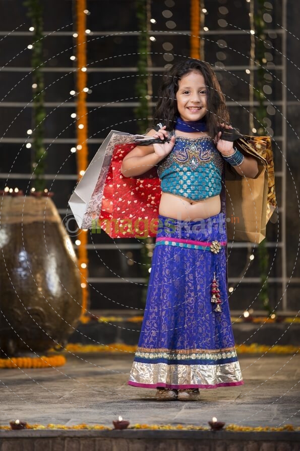 cheerful little girl carrying shopping bags on diwali