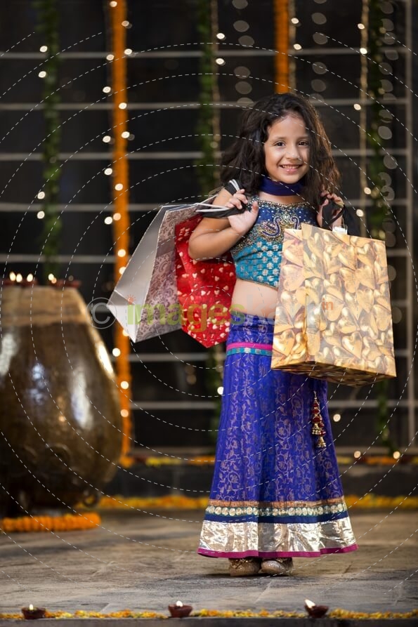 cheerful little girl carrying shopping bags on diwali