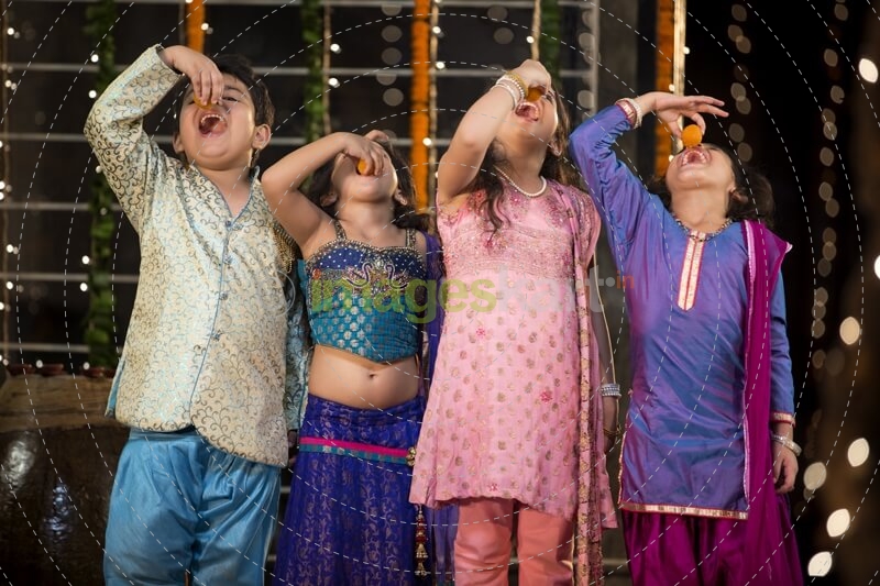 traditional indian kids enjoying laddu on diwali