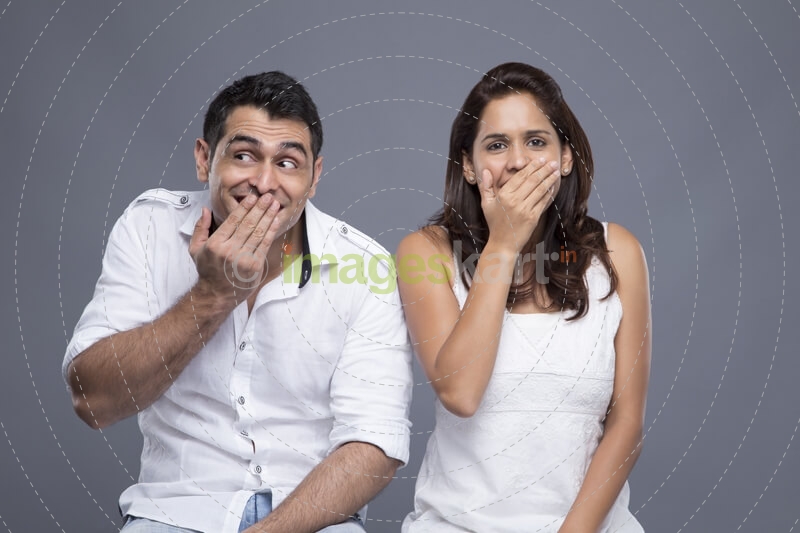 couple with mouth covered by hands 