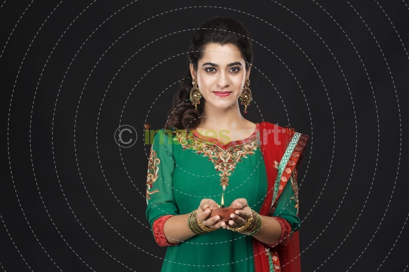 girl posing with diya in traditional wear