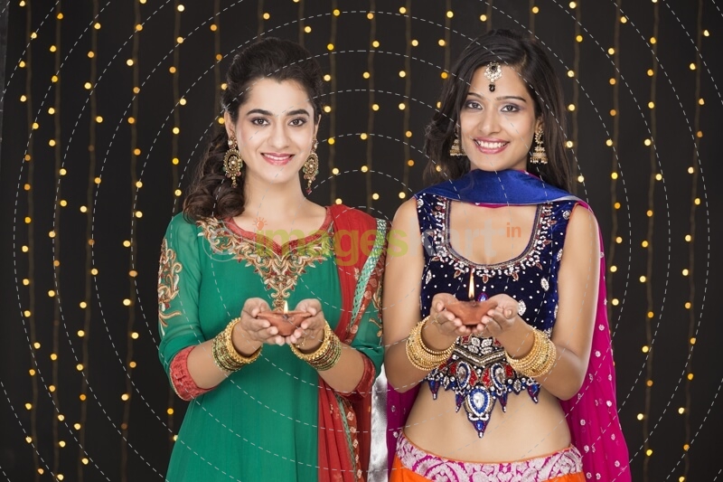 girls in indian wear posing with diyas 