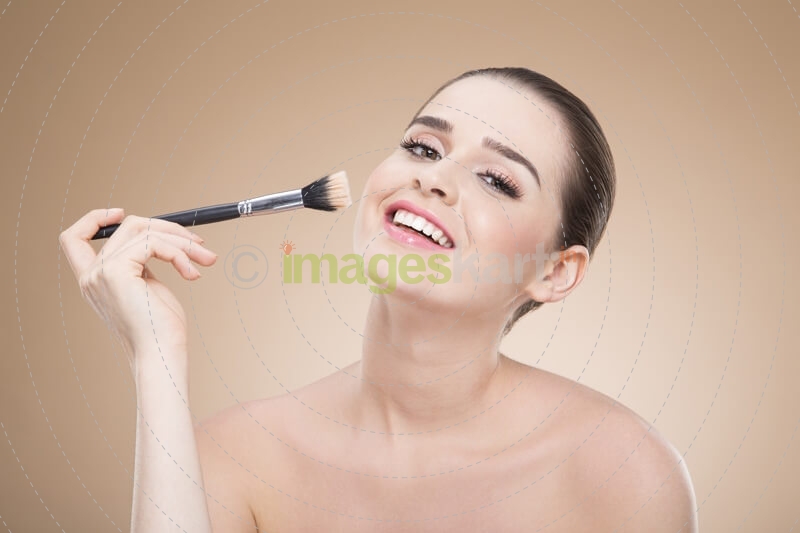 girl applying make up with brush while posing 