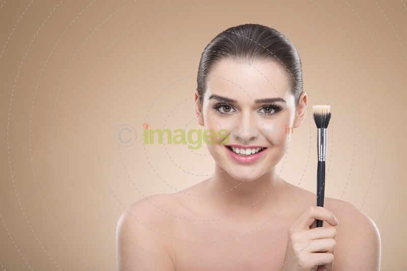 girl posing with make up brush and smiling
