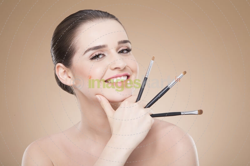 girl posing with make up brush and smiling