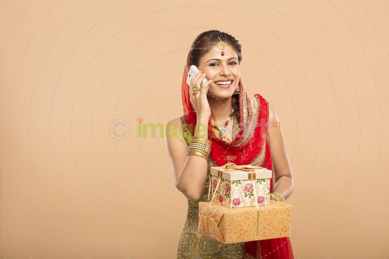 woman talking on phone while holding gifts