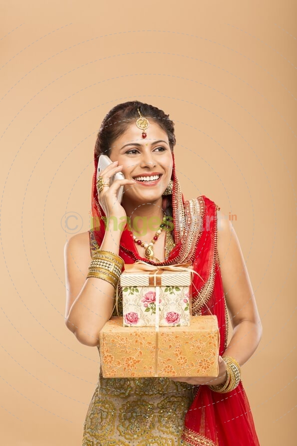 woman talking on phone while holding gifts