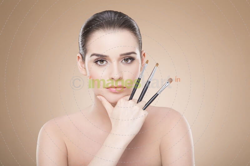 girl posing with make up brush while looking at the camera
