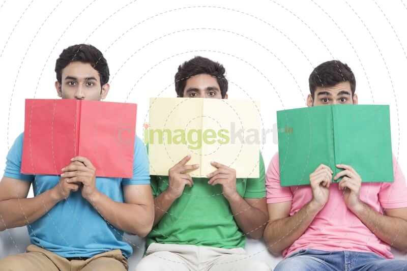 three friends sitting in a row hiding faces with books