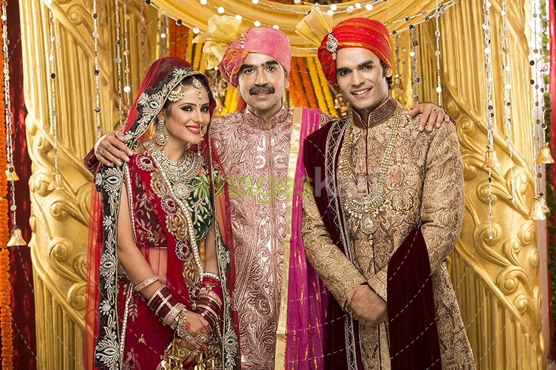 bride and groom posing with father 