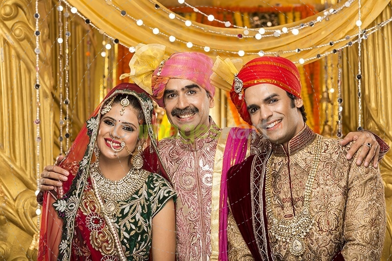 bride and groom posing with father 