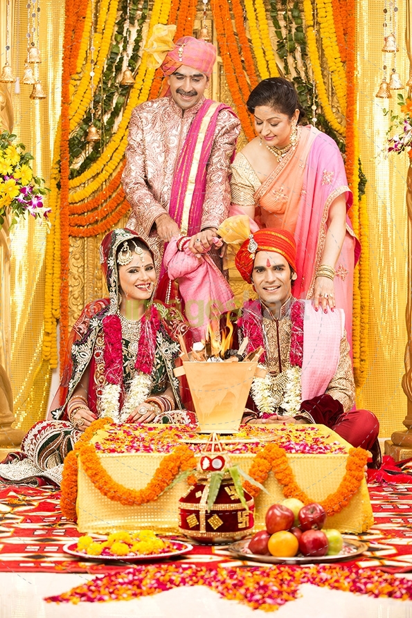 indian bride and groom sitting with parents at mandap