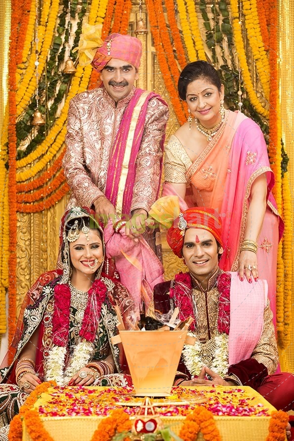 indian bride and groom sitting with parents at mandap