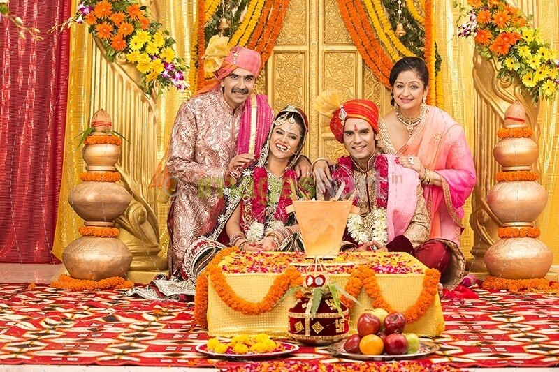 indian bride and groom sitting with parents at mandap