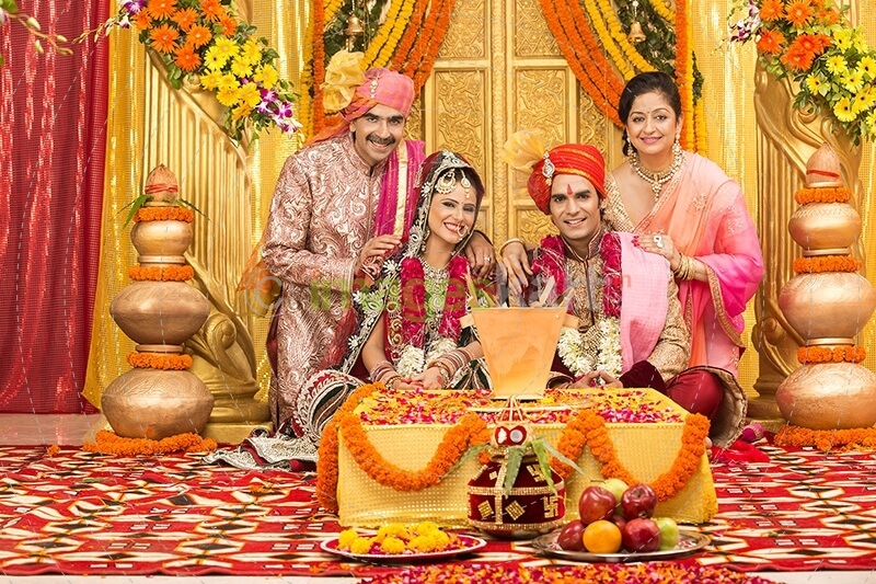 indian bride and groom sitting with parents at mandap