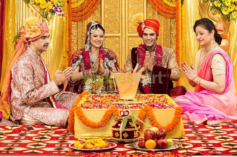 indian bride and groom sitting with parents at mandap