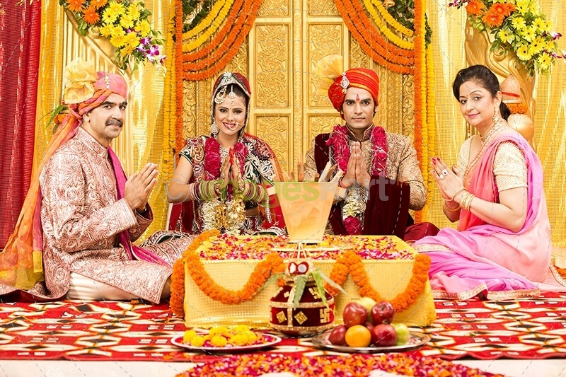 indian bride and groom sitting with parents at mandap