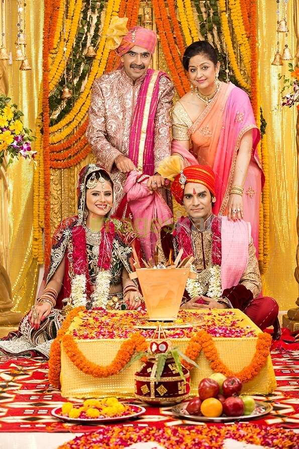 indian bride and groom sitting with parents at mandap