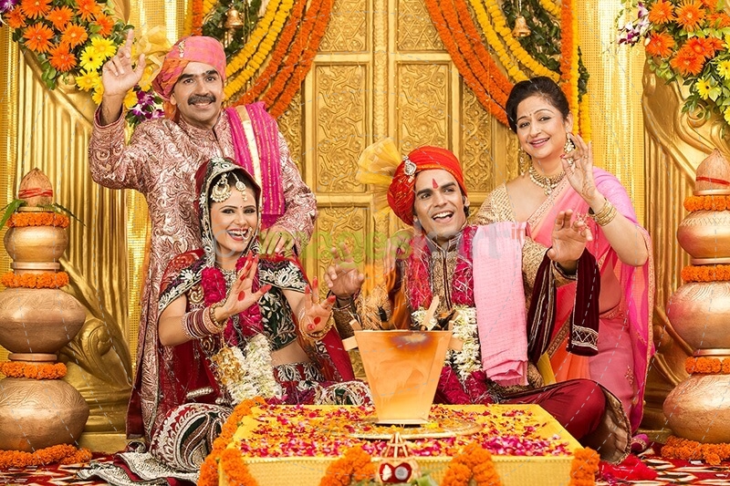 indian bride and groom sitting with parents at mandap