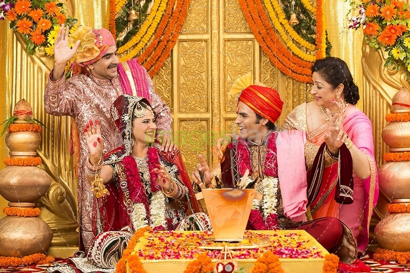 indian bride and groom sitting with parents at mandap